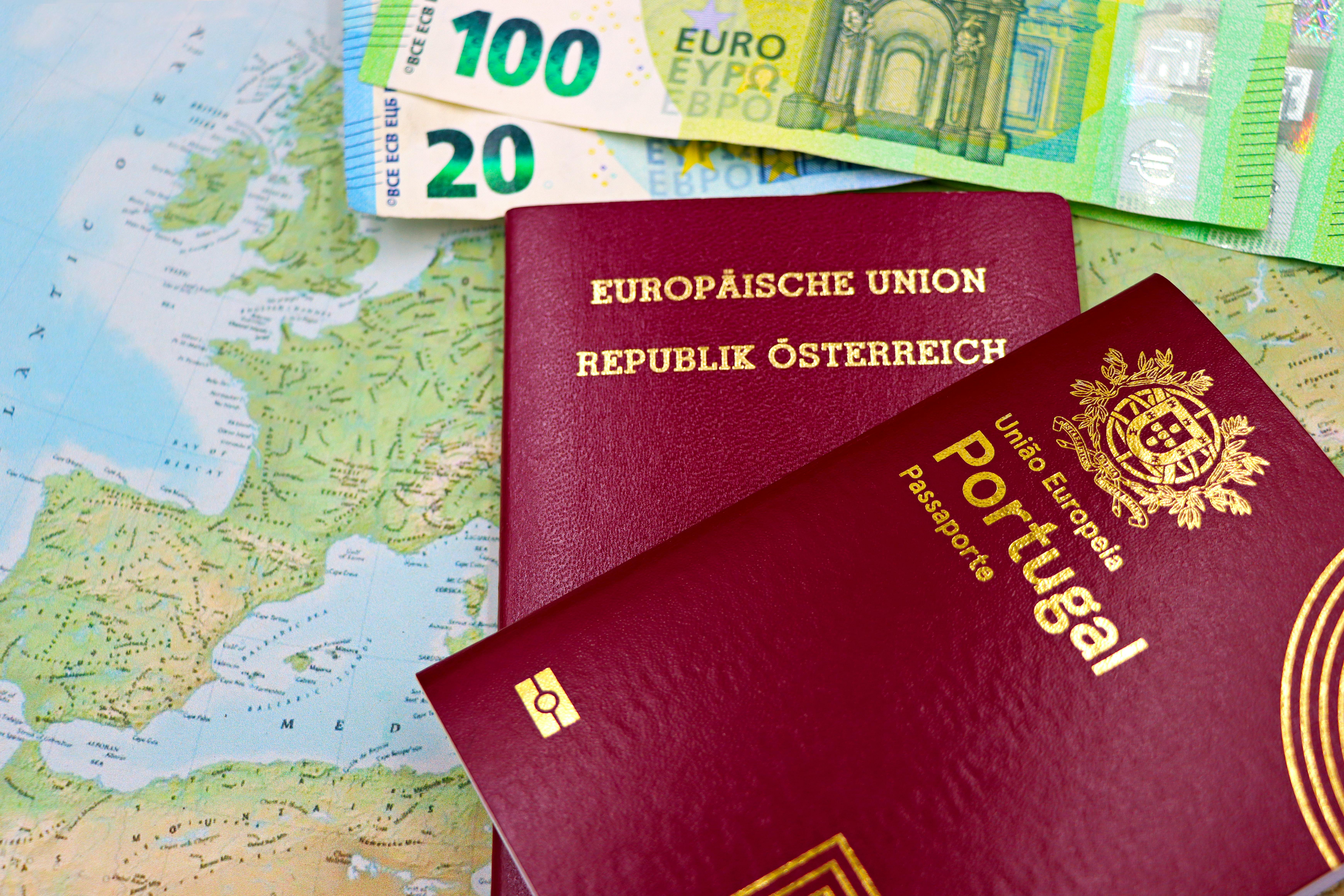 Free Austrian and Portuguese passports on a European map with euro banknotes. Stock Photo