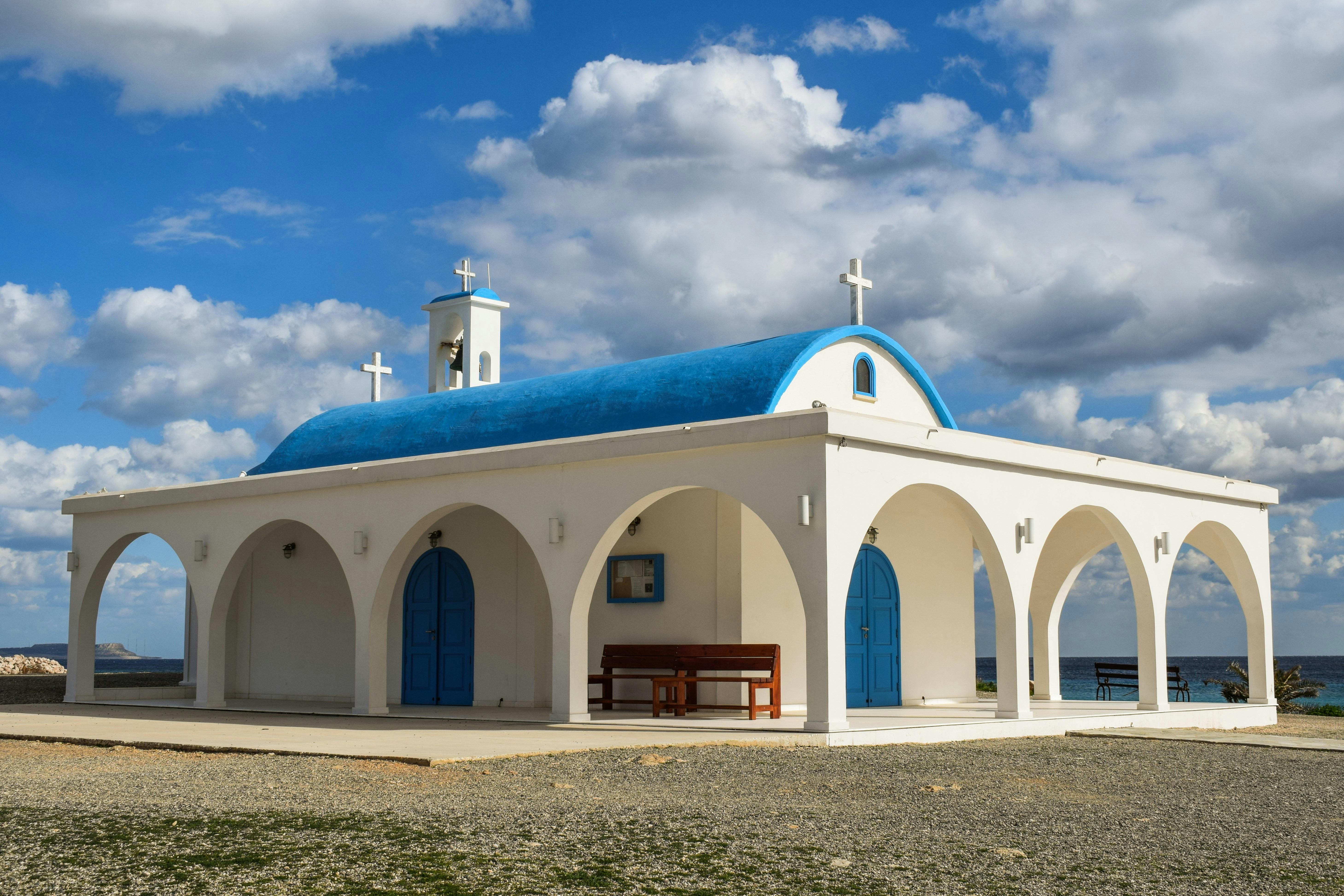 Free A picturesque white chapel with a blue dome set against a bright sky in Cyprus. Stock Photo